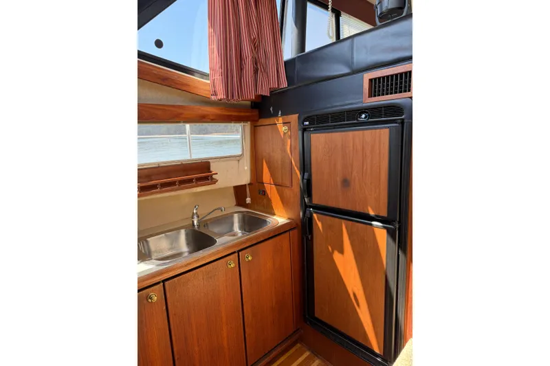Slide: The Image of 1994 Bayliner 3888 MY Sedan kitchen with wood cabinets, double sink, and refrigerator. - 30