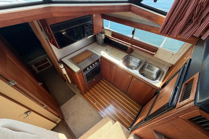 Slide: The Image of 1994 Bayliner 3888 MY Sedan yacht kitchen with wood cabinetry and dual sinks. - 31