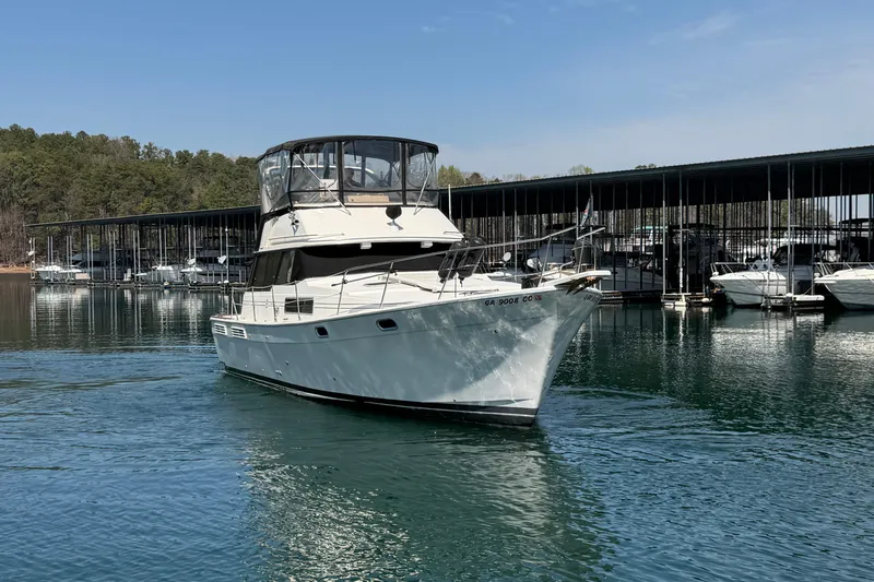 Slide: The Image of 1994 Bayliner 3888 MY Sedan yacht docked on a serene lake with marina backdrop. - 4