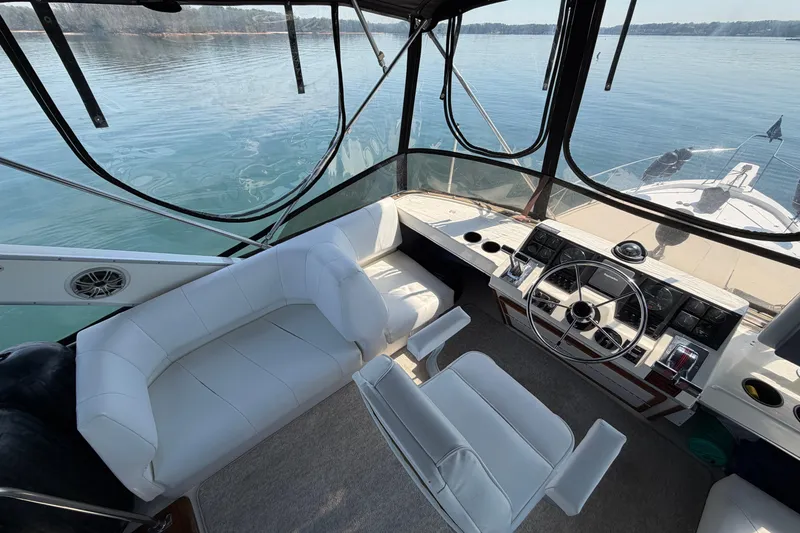 Slide: The Image of 1994 Bayliner 3888 MY Sedan helm with white seating, overlooking calm waters. - 48