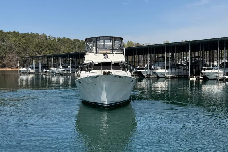 Slide: The Image of 1994 Bayliner 3888 MY Sedan docked at marina, surrounded by calm water and trees. - 5