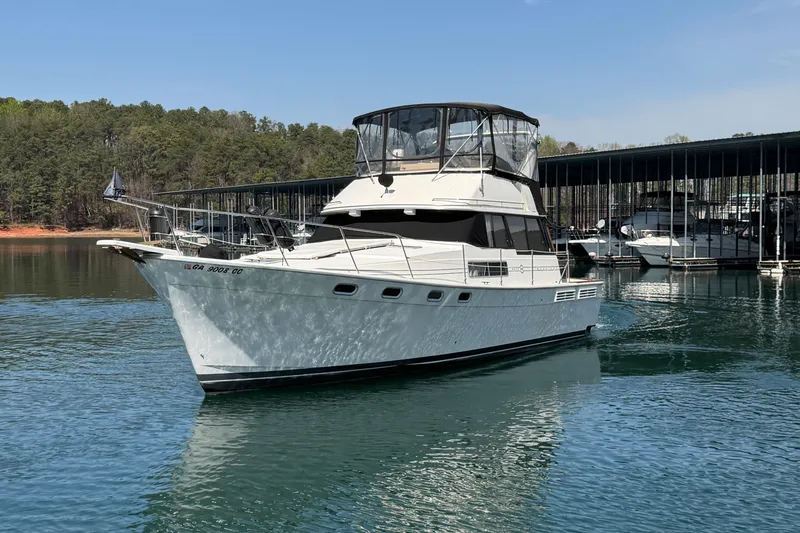 Slide: The Image of 1994 Bayliner 3888 MY Sedan yacht docked on a serene lake with forest backdrop. - 7