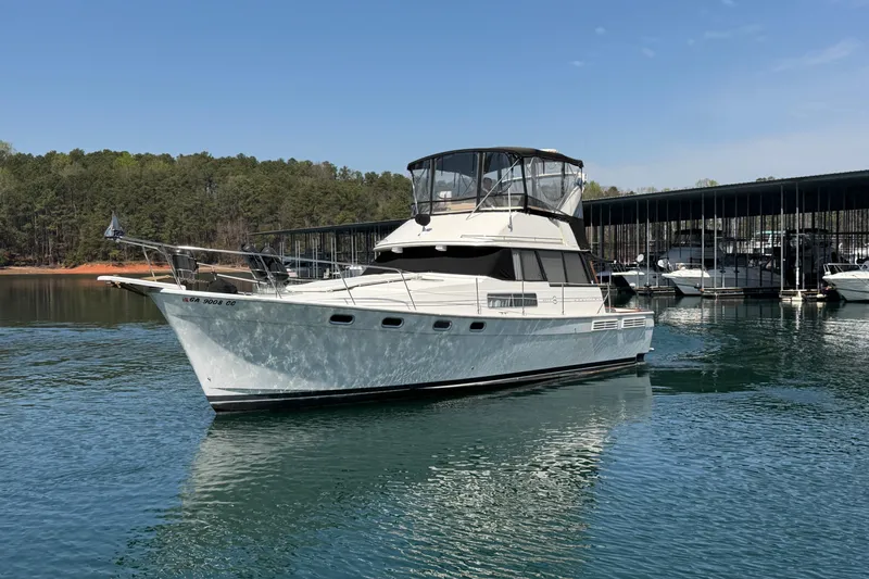 Slide: The Image of 1994 Bayliner 3888 MY Sedan yacht on a serene lake with forested background. - 8