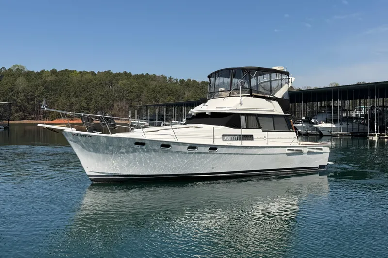 Slide: The Image of 1994 Bayliner 3888 MY Sedan yacht on a serene lake with forested background. - 9