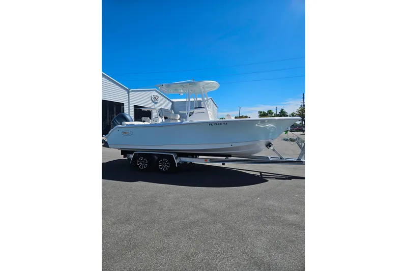 Slide: The Image of 2023 Sea Hunt Ultra 229 boat on trailer, parked outdoors under clear blue sky. - 4
