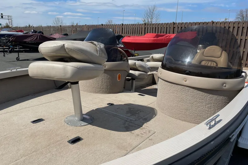 Slide: The Image of 2003 Crestliner 1850 Fish Hawk SC boat interior with seating and windshield, parked outdoors. - 4