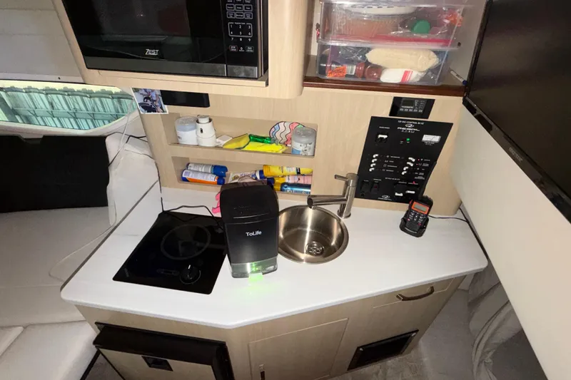 Slide: The Image of 2023 Regal 26 XO boat interior kitchen with sink, stove, and microwave. - 122