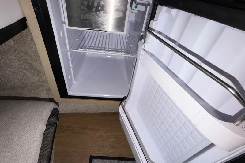 Slide: The Image of Open mini fridge inside 2023 Regal 26 XO boat cabin. - 124