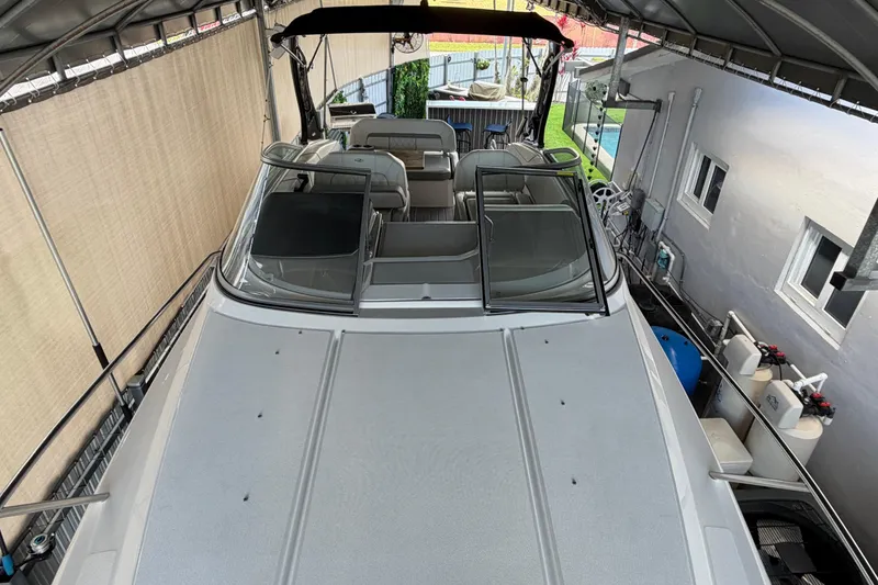 Slide: The Image of 2023 Regal 26 XO boat docked under a canopy, showcasing sleek design and spacious interior. - 169