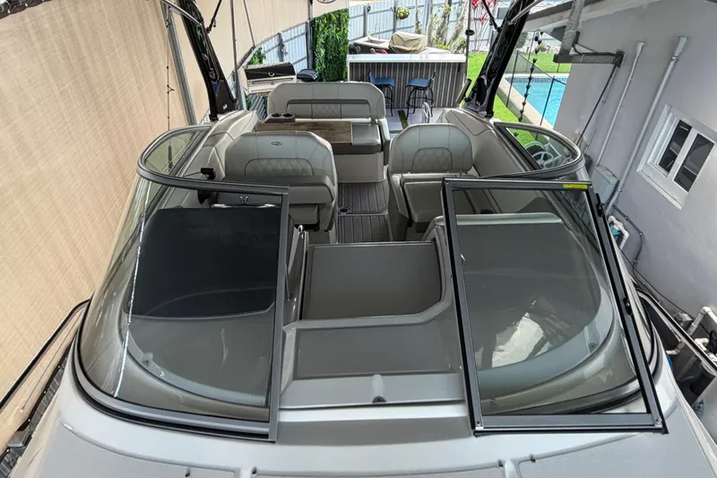 Slide: The Image of 2023 Regal 26 XO boat interior with seating and windshield, docked near a pool. - 171
