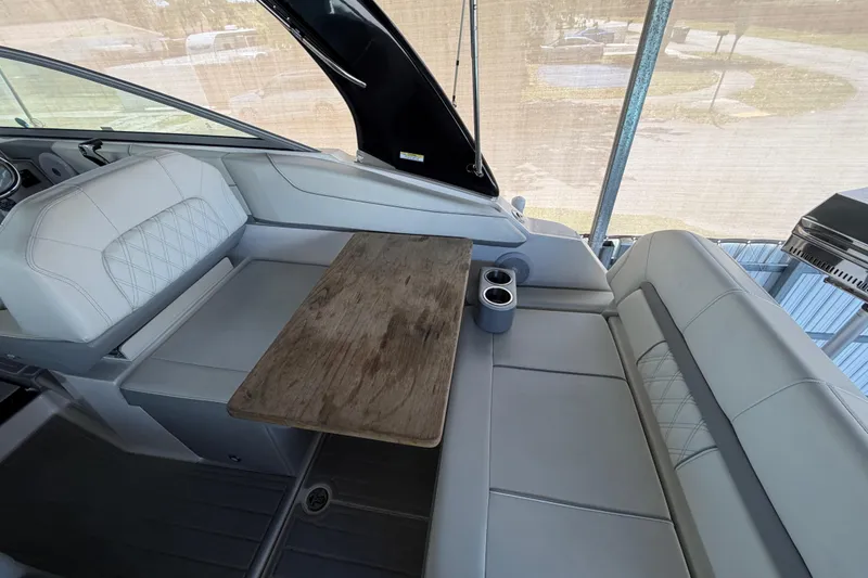 Slide: The Image of 2023 Regal 26 XO boat interior with seating, wooden table, and cup holders. - 73