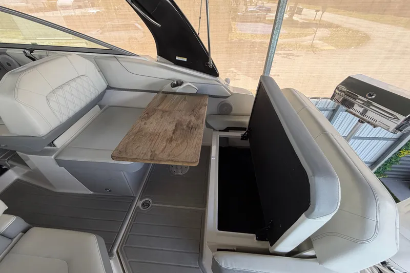 Slide: The Image of 2023 Regal 26 XO boat interior with seating, wooden table, and storage compartment. - 74