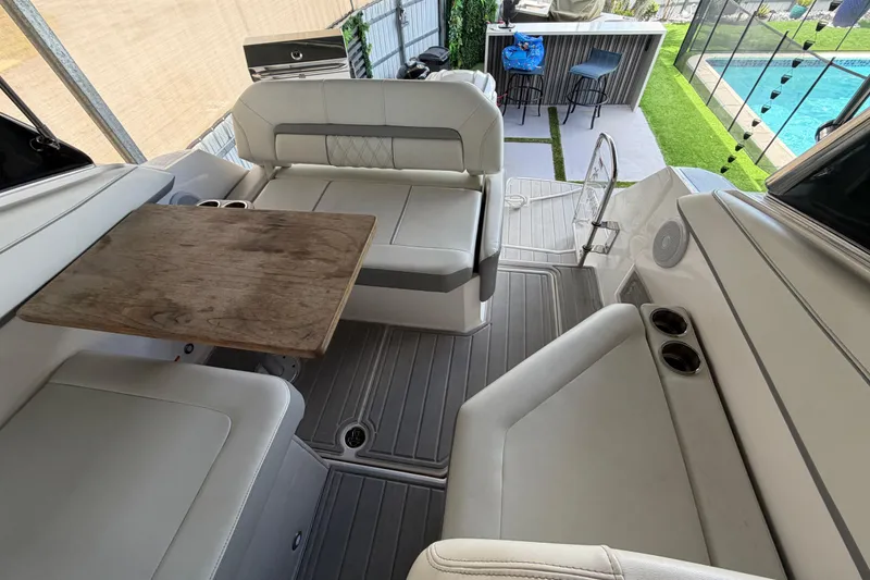 Slide: The Image of 2023 Regal 26 XO boat interior with seating, table, and poolside view. - 84