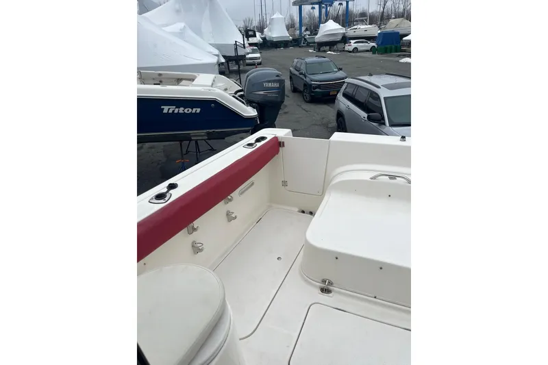 Slide: The Image of 2006 Trophy 2359 Hardtop boat interior with docked vehicles and covered boats in background. - 11