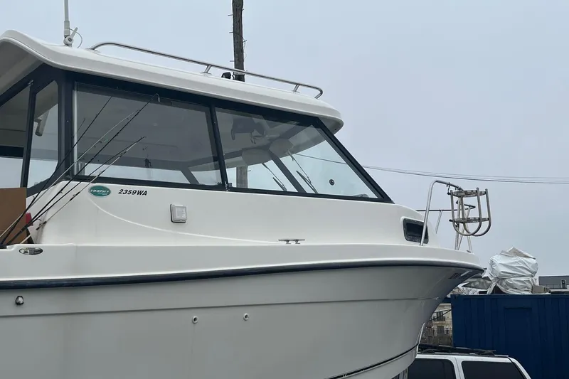 Slide: The Image of 2006 Trophy 2359 Hardtop boat with fishing rods, docked on a cloudy day. - 23