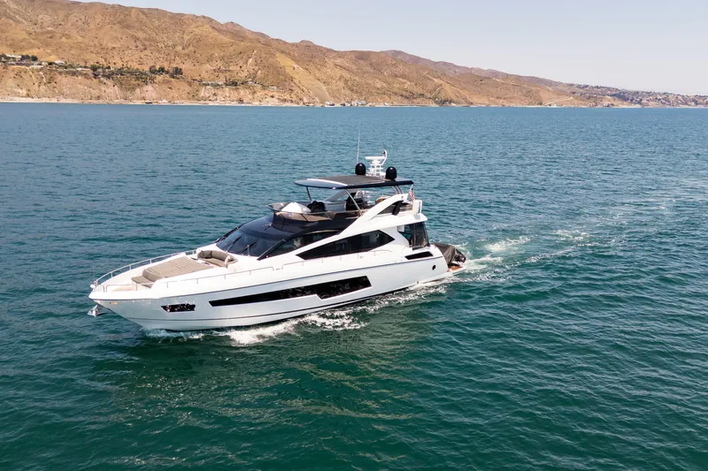The Image of Luxurious 2015 Sunseeker 75 Yacht cruising on open sea near scenic coastline. - 1