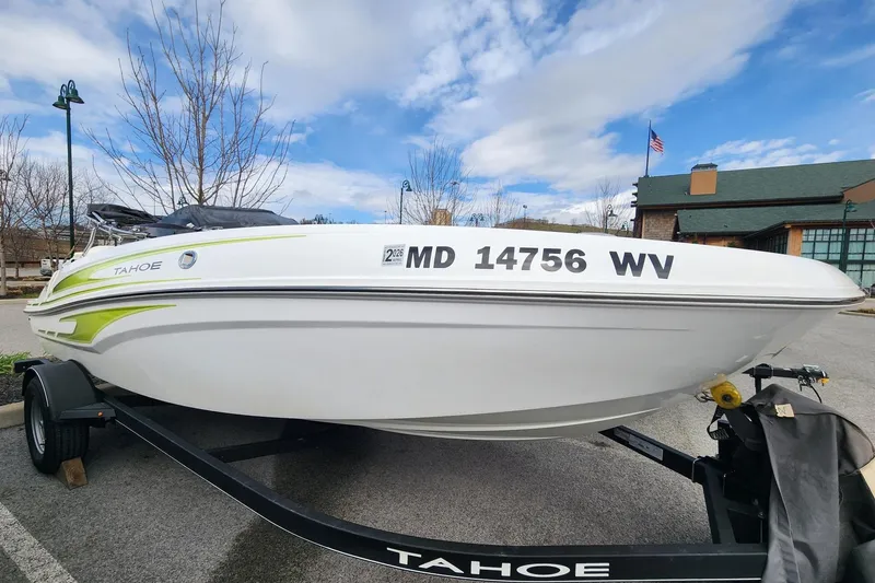 The Image of 2023 Tahoe T18 boat on trailer, parked outdoors under a partly cloudy sky. - 0