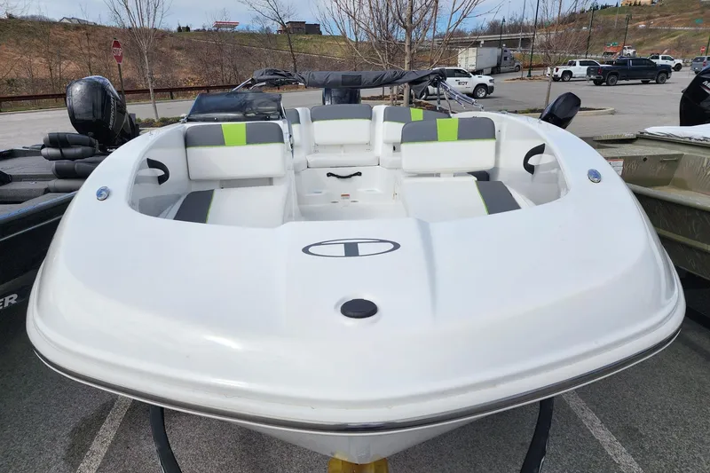 Slide: The Image of 2023 Tahoe T18 boat with sleek white design and green accents, parked outdoors. - 2