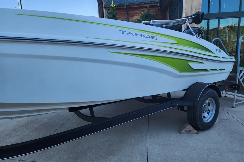 Slide: The Image of 2023 Tahoe T18 boat with green accents on a trailer, parked outdoors. - 6