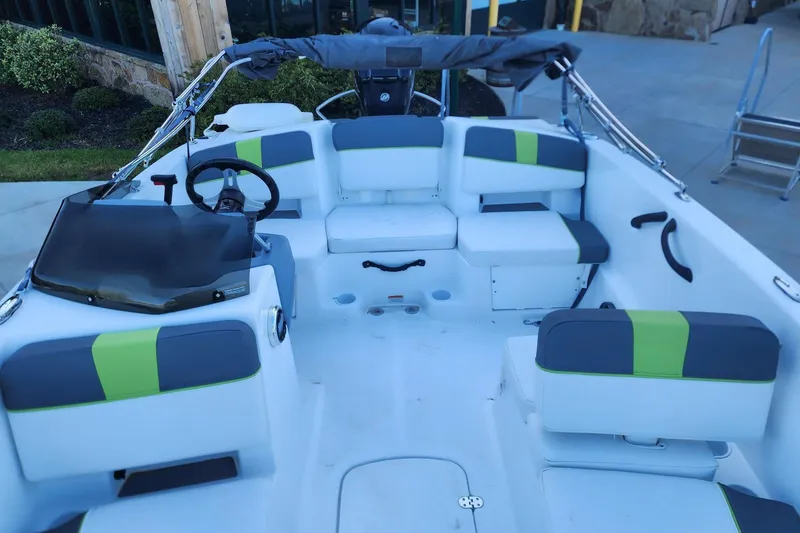 Slide: The Image of 2023 Tahoe T18 boat interior with modern seating and steering wheel, docked outdoors. - 9