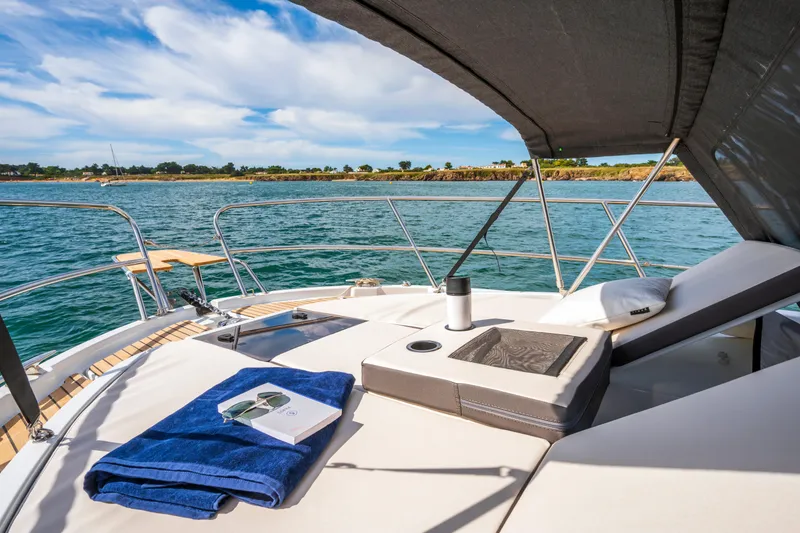 Slide: The Image of Luxurious 2026 Beneteau Antares 11 Coupe yacht deck with sunbed, towel, and scenic ocean view. - 10