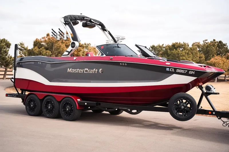 Slide: The Image of 2019 MasterCraft X24 boat on trailer, red and gray design, parked outdoors. - 1