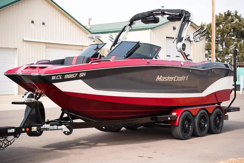 Slide: The Image of 2019 MasterCraft X24 boat on trailer, red and black design, parked near buildings. - 3