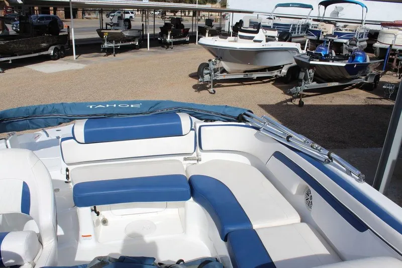 Slide: The Image of 2020 Tahoe 215 Xi boat with blue and white seating, parked in a marina. - 12