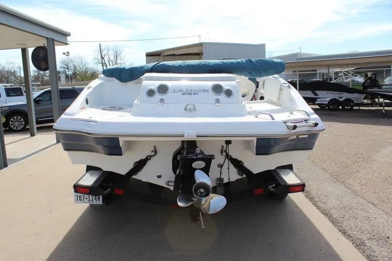 Slide: The Image of 2020 Tahoe 215 Xi boat rear view, parked outdoors with covered seating area. - 3