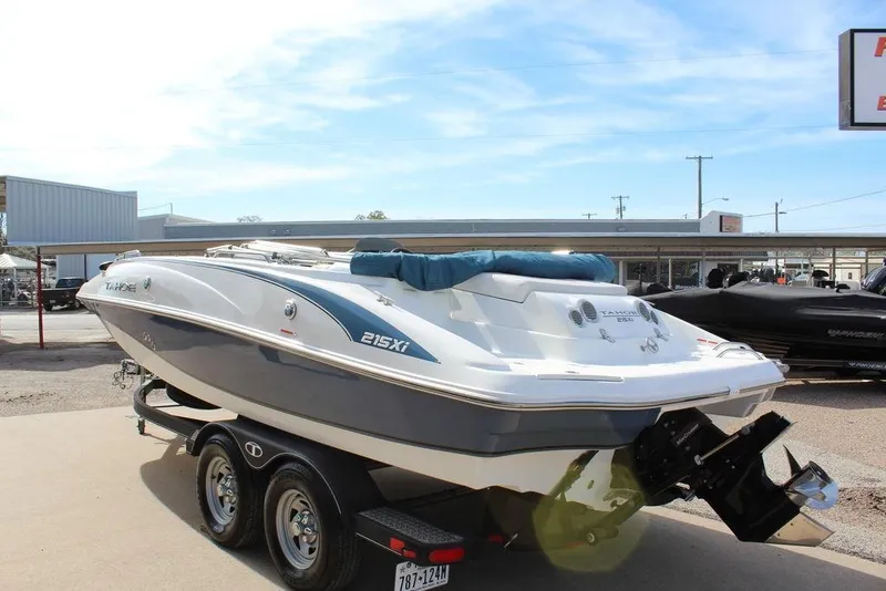 Slide: The Image of 2020 Tahoe 215 Xi boat on trailer, parked outdoors under clear sky. - 4