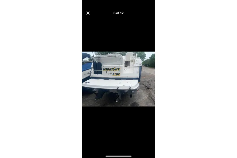 Slide: The Image of Rear view of a 2005 Regal 2750 boat named "Midnight Blue" parked on land. - 5