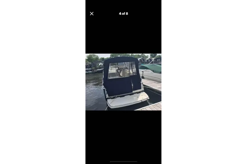 Slide: The Image of 2005 Regal 2750 boat docked with blue canopy, rear view. - 6