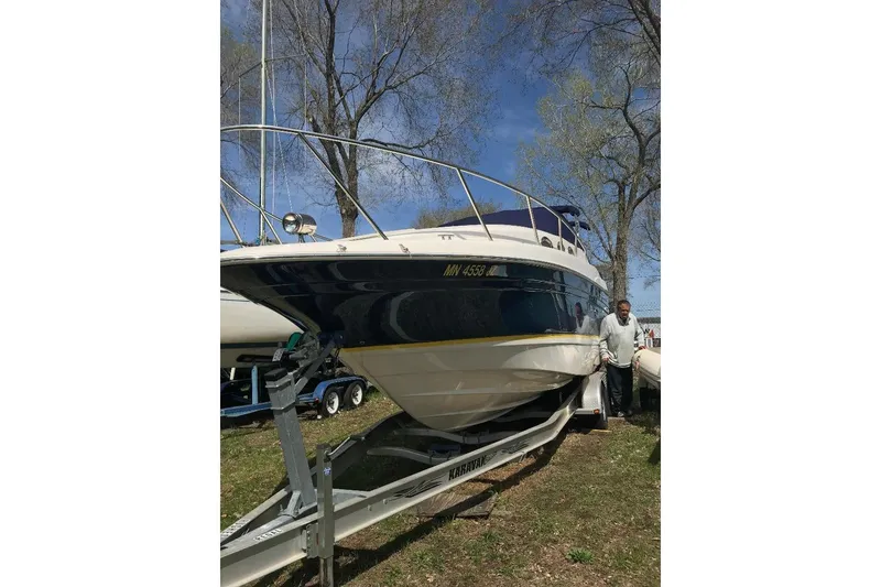 Slide: The Image of 2005 Regal 2750 boat on trailer, parked outdoors with trees in the background. - 9