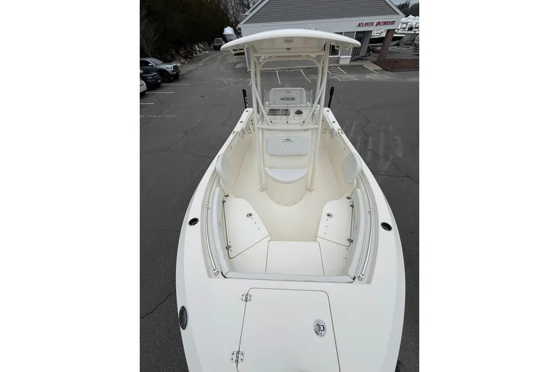 Slide: The Image of 2022 Cobia 220 Center Console boat with spacious deck and seating, parked outdoors. - 21