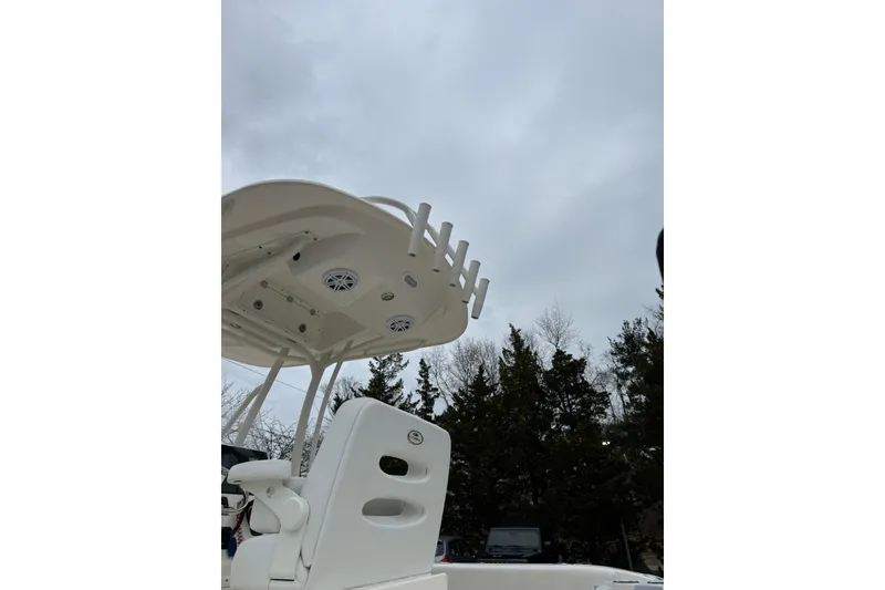 Slide: The Image of 2022 Cobia 220 Center Console boat with T-top and rod holders under cloudy sky. - 26