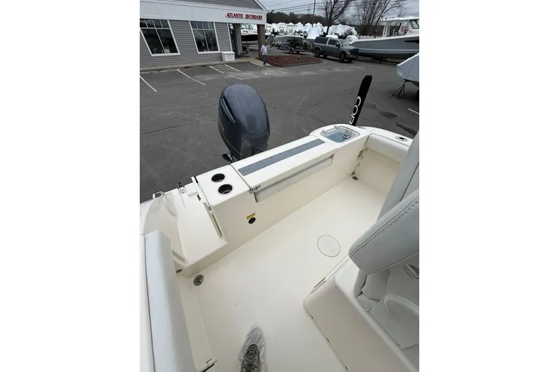 Slide: The Image of 2022 Cobia 220 Center Console boat interior with motor, parked outside dealership. - 4