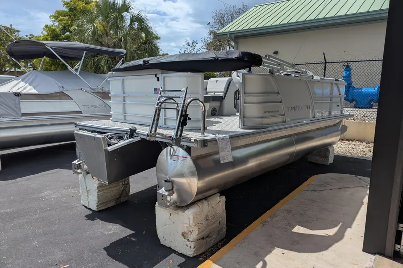 Slide: The Image of 2026 Trifecta 20CLE pontoon boat displayed outdoors, featuring sleek aluminum design. - 2
