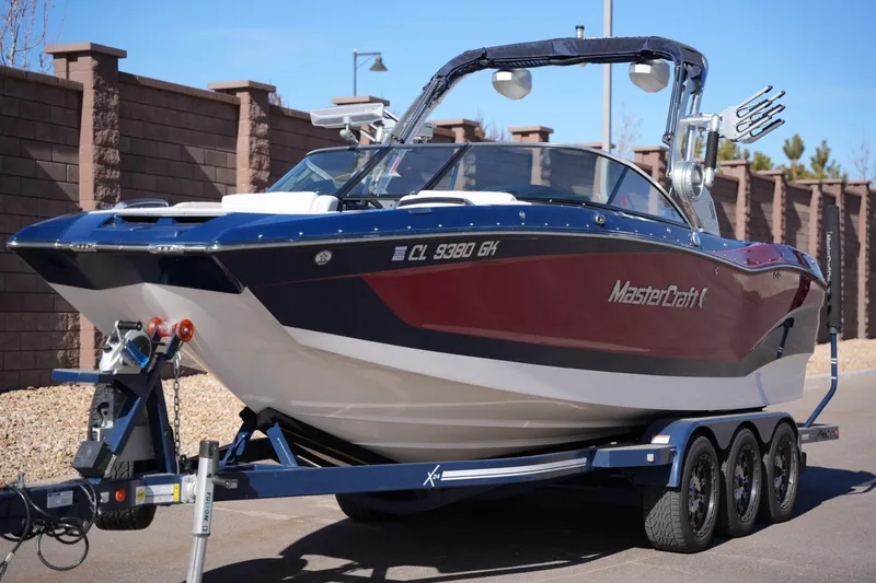 Slide: The Image of 2019 MasterCraft X24 boat on trailer, parked outdoors, showcasing sleek design and vibrant colors. - 8