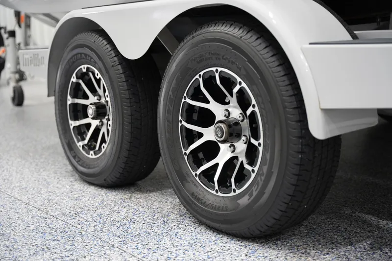 Slide: The Image of 2020 Malibu Wakesetter 21 VLX trailer wheels on a speckled garage floor. - 19