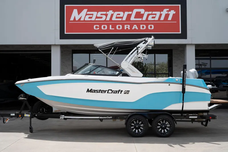 The Image of 2022 MasterCraft XT22 boat in blue and white, displayed at MasterCraft Colorado dealership. - 1
