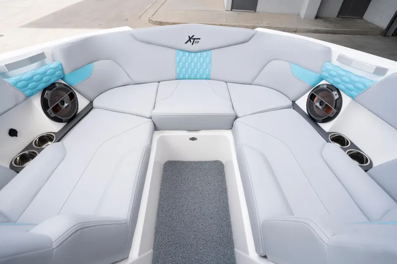 Slide: The Image of 2022 MasterCraft XT22 boat interior with white and blue seating, speakers, and cup holders. - 11