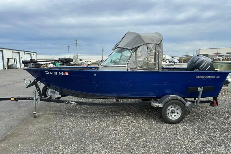 The Image of 2014 Lowe Fishing Machine 165WT Pro boat on trailer, blue exterior, parked outdoors. - 1