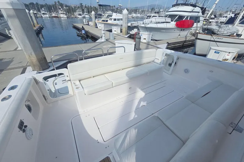 Slide: The Image of Spacious deck of 2001 Tiara Yachts 5200 Express at marina, featuring white seating. - 5
