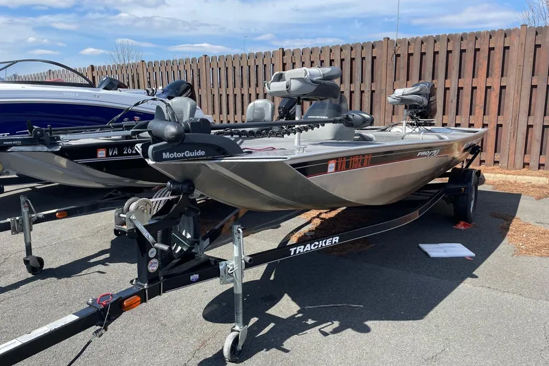 Slide: The Image of 2014 Tracker Pro 170 boat on trailer, parked outdoors near wooden fence. - 2