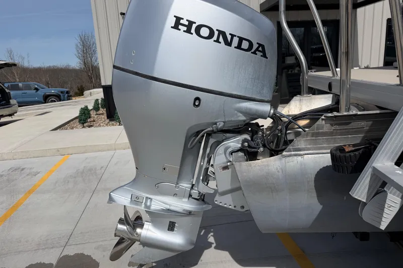 Slide: The Image of 2018 Godfrey Sweetwater 2486 SB with Honda outboard motor in a parking lot. - 12