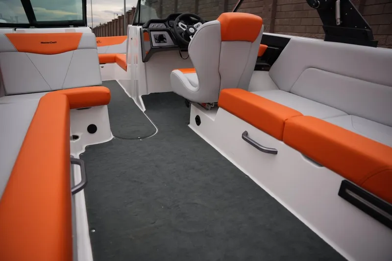 Slide: The Image of 2021 MasterCraft NXT24 boat interior with orange and gray seating, modern dashboard. - 15