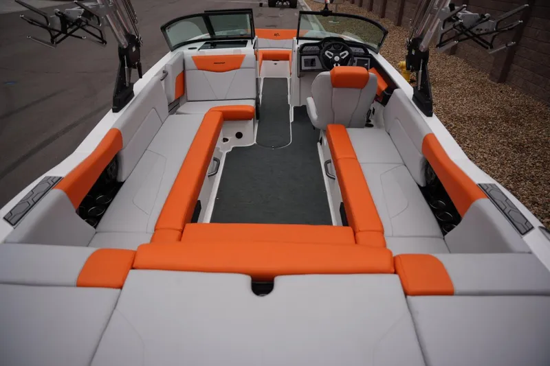 Slide: The Image of 2021 MasterCraft NXT24 boat interior with orange and white seating, modern dashboard. - 18