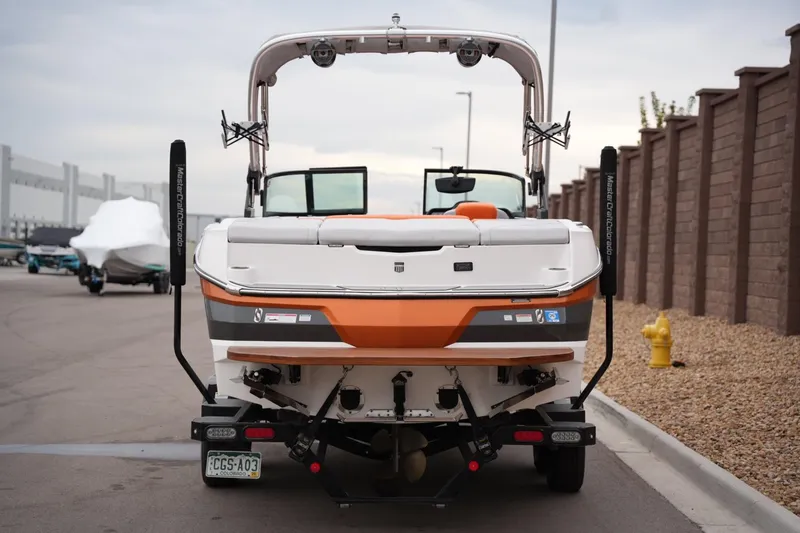 Slide: The Image of 2021 MasterCraft NXT24 boat, rear view, parked on a street near a brick wall. - 3