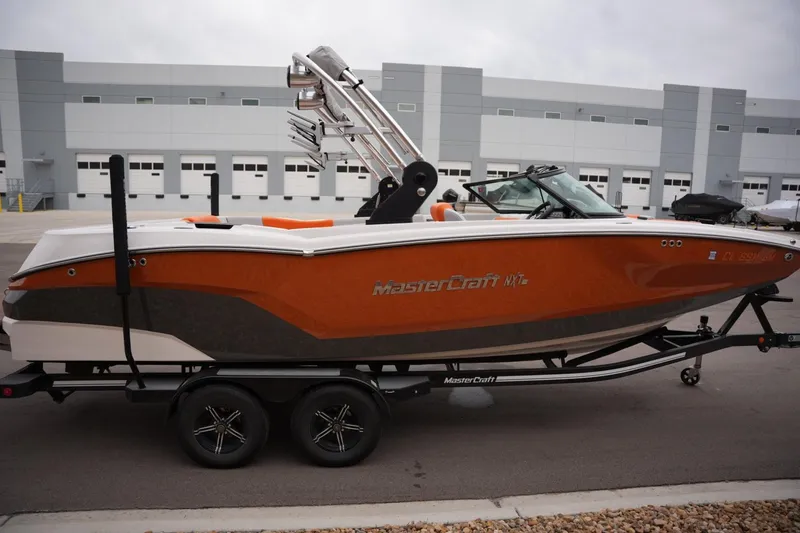 Slide: The Image of 2021 MasterCraft NXT24 boat in orange and white on a trailer. - 5