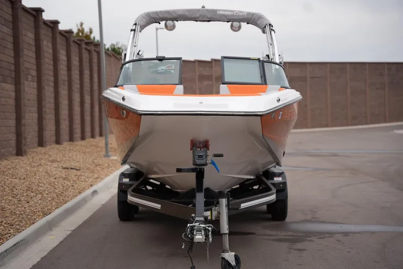 Slide: The Image of 2021 MasterCraft NXT24 boat on trailer, parked on a paved road. - 7